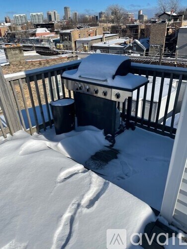 A BBQ grill on a snow-covered balcony.