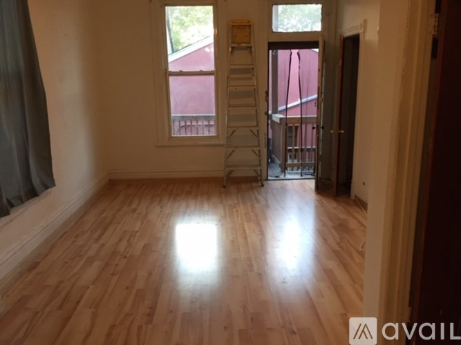 A room with wooden flooring and a ladder in it.