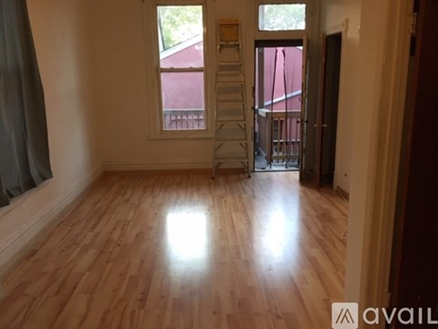 A room with wooden flooring and a ladder in it.