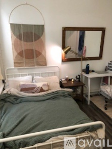 A bedroom with a bed, nightstand, and a mirror on the wall.