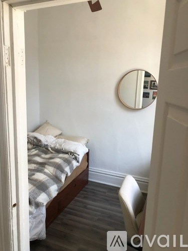A bedroom with a bed, chair, and mirror.