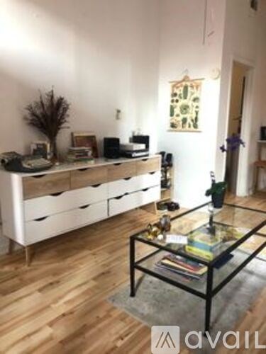 A room with a glass coffee table and a white cabinet with drawers.
