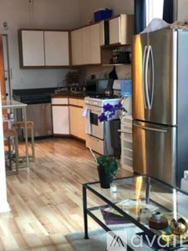 A kitchen with a stainless steel refrigerator and wooden floors.