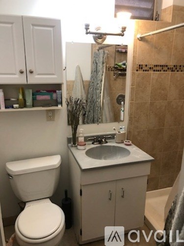 A bathroom with a toilet, sink, and shower.