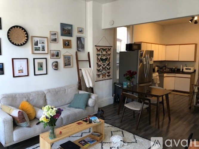 A living room with a grey couch, a wooden coffee table, and a wall with framed pictures.