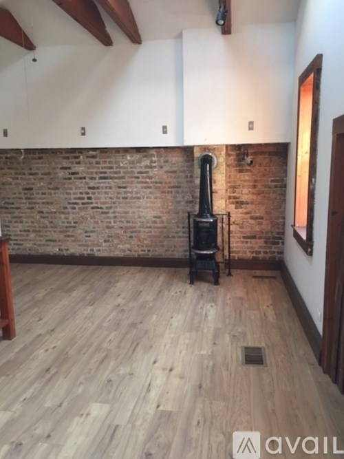 A room with a wood floor and a brick wall.