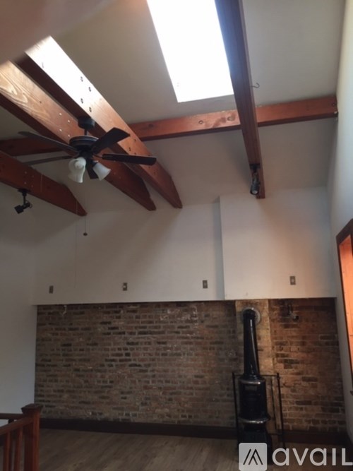 A room with a ceiling fan and a brick wall.