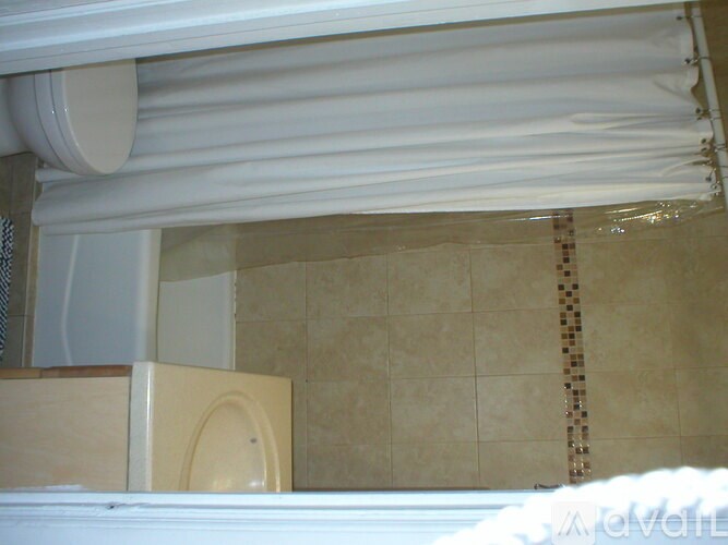 A bathroom with a toilet and a tiled wall.