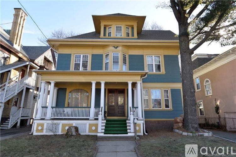 A yellow and green two-story house with a porch.