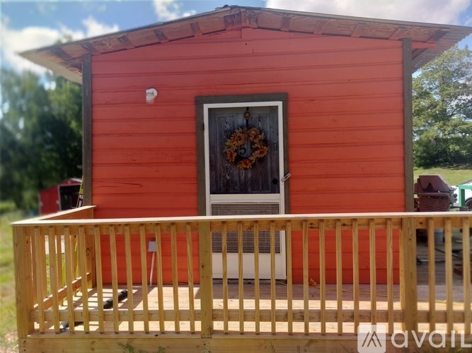 A small red house with a wooden fence in front.
