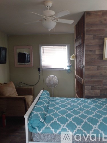 A bedroom with a bed, a couch, a ceiling fan, and a window with blinds.