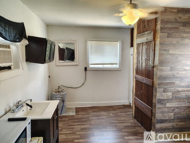 A small room with a bed, a microwave, and a fridge.