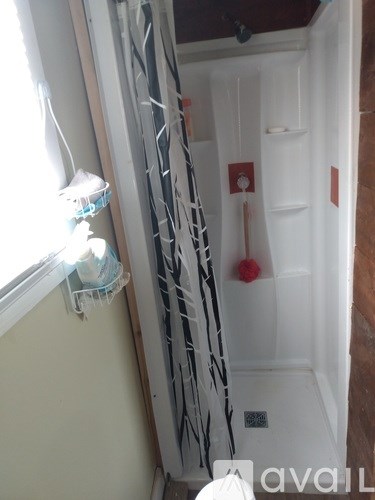 A white toilet is in a small bathroom with a white shower stall.