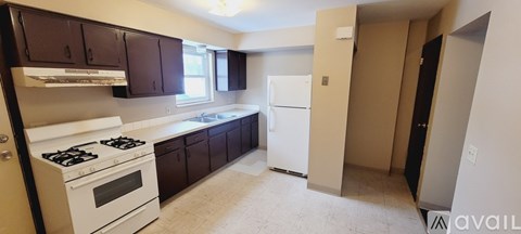 A kitchen with white appliances and dark brown cabinets.