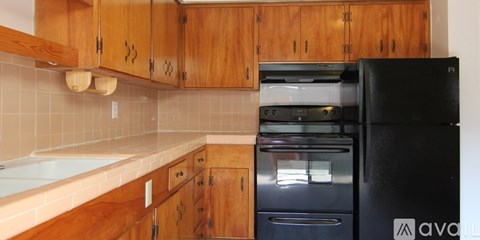 A kitchen with wooden cabinets and a black fridge.