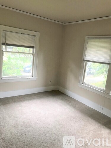 A room with two windows and carpeted floor.