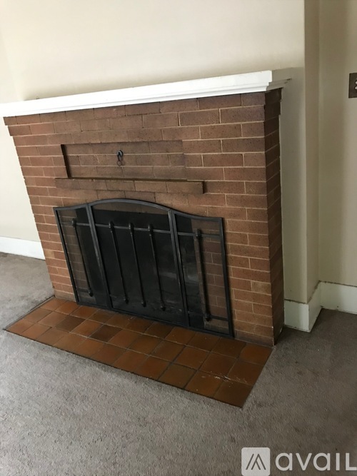 A brick fireplace with a black grate in the middle.