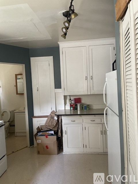 A kitchen with white cabinets and a white refrigerator.