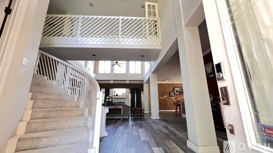 A staircase with a white railing leads to a living room.