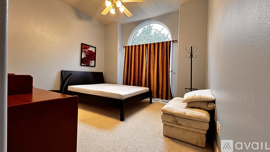 A bedroom with a bed, a chair, and a ceiling fan.