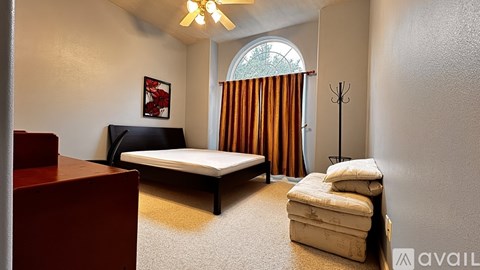 A bedroom with a bed, a chair, and a ceiling fan.