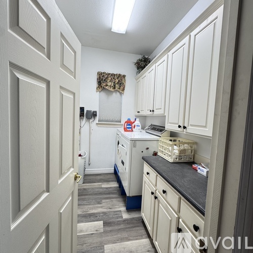 A kitchen with white cabinets and a door on the left.