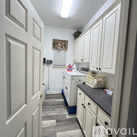 A kitchen with white cabinets and a door on the left.