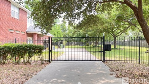 A black gate blocks the entrance to a driveway.