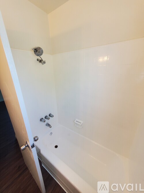 A white bathroom with a tub and a shower head.