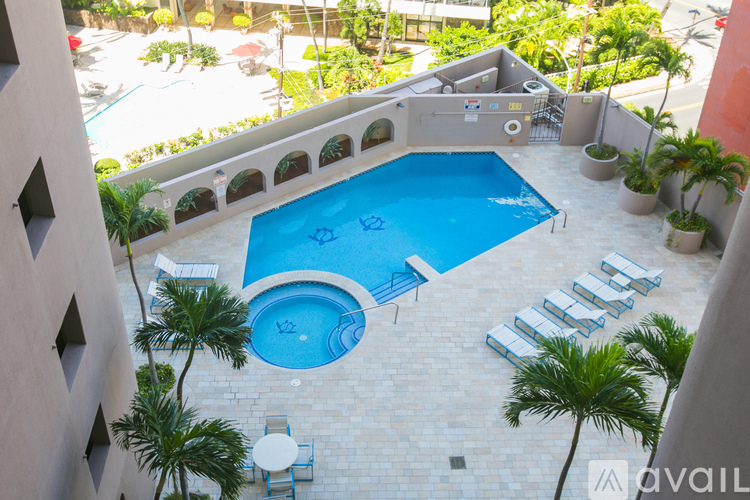 A small pool surrounded by a balcony and palm trees.