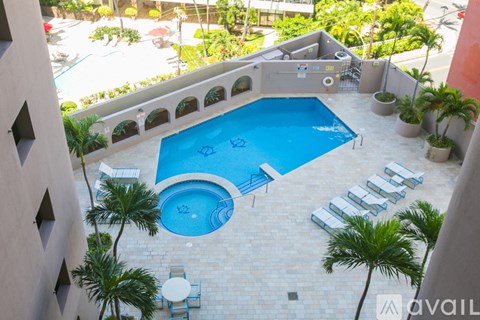 A small pool surrounded by a balcony and palm trees.
