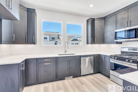 A modern kitchen with dark grey cabinets and stainless steel appliances.