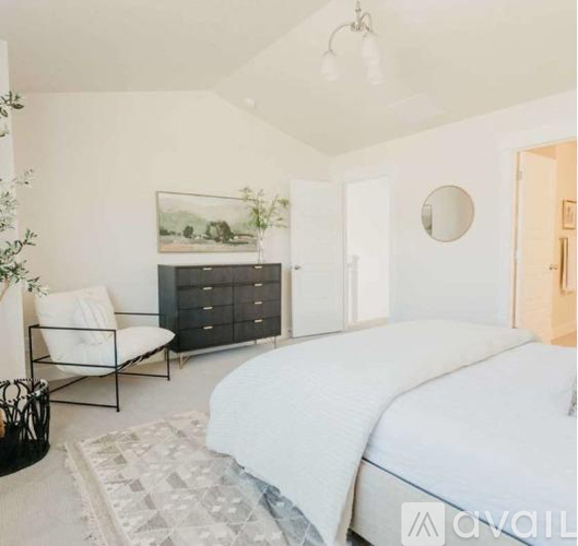 A bedroom with a large bed, a chair, and a painting on the wall.