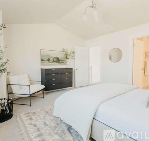 A bedroom with a large bed, a chair, and a painting on the wall.