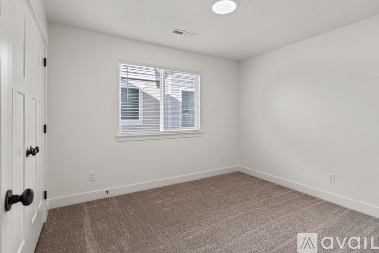 A room with a carpeted floor and a window with blinds.