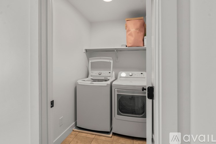 A kitchen with a white wall and a brown bag on top of the cabinet.