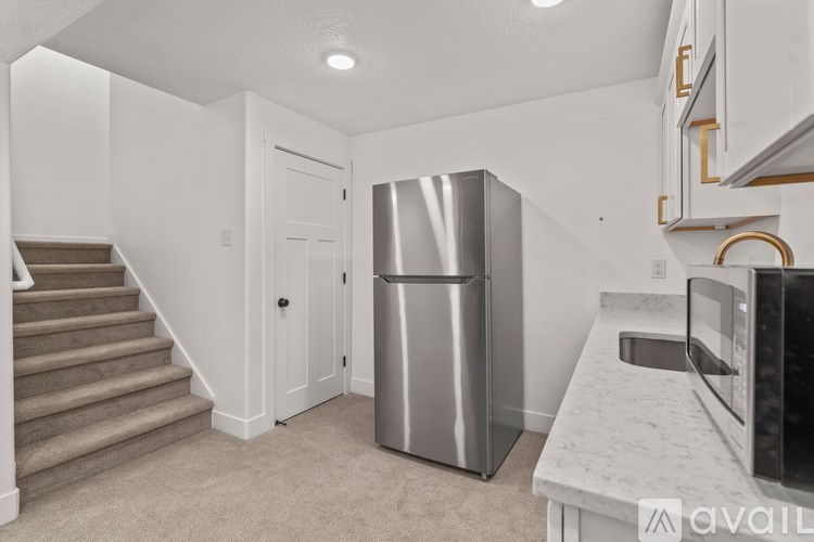 A kitchen area with a refrigerator, microwave, and stairs leading to another room.