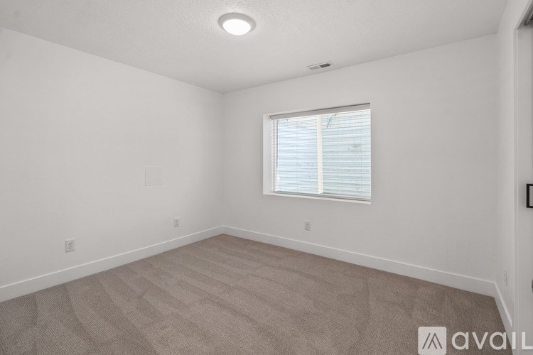 A room with a carpeted floor and a window with blinds.