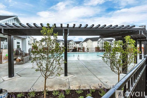 A patio with a pergola and a pool in the background.