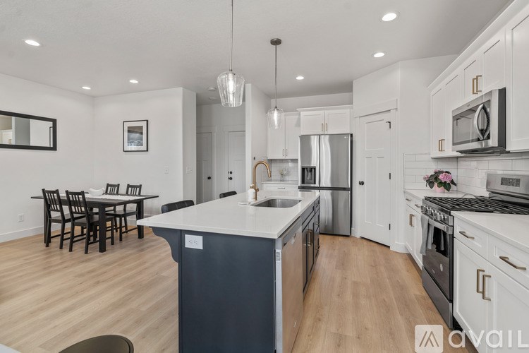 A modern kitchen with white cabinets and a wooden floor.
