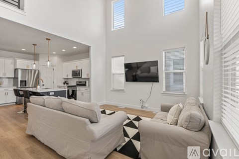 A modern living room with a large couch and a kitchen area in the background.
