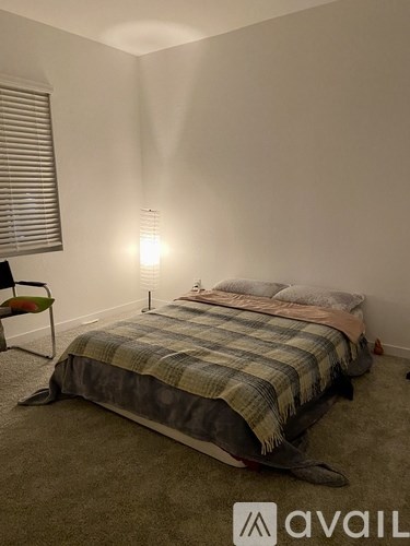 A bedroom with a bed, chair, and lamp.