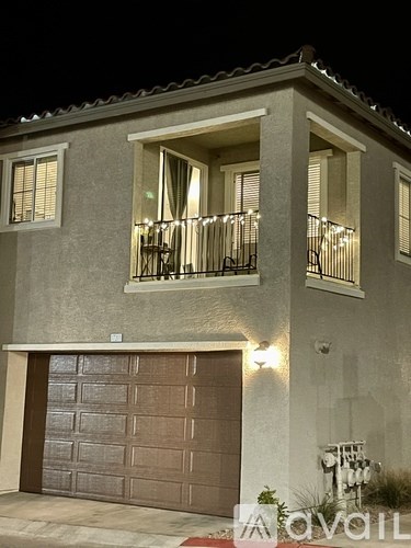 A house with a garage and a balcony with lights on.