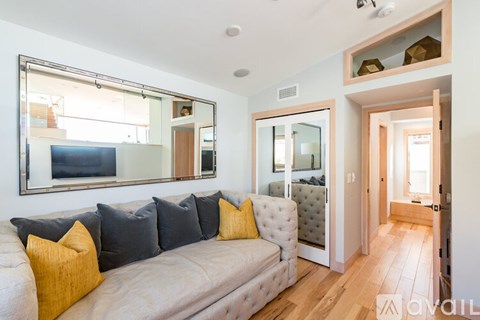 A living room with a grey couch and yellow pillows.