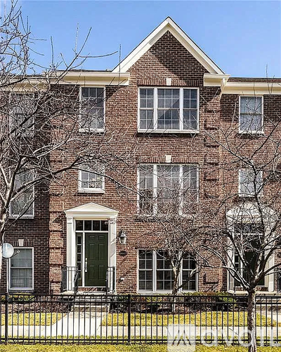 A red brick building with a black fence in front.