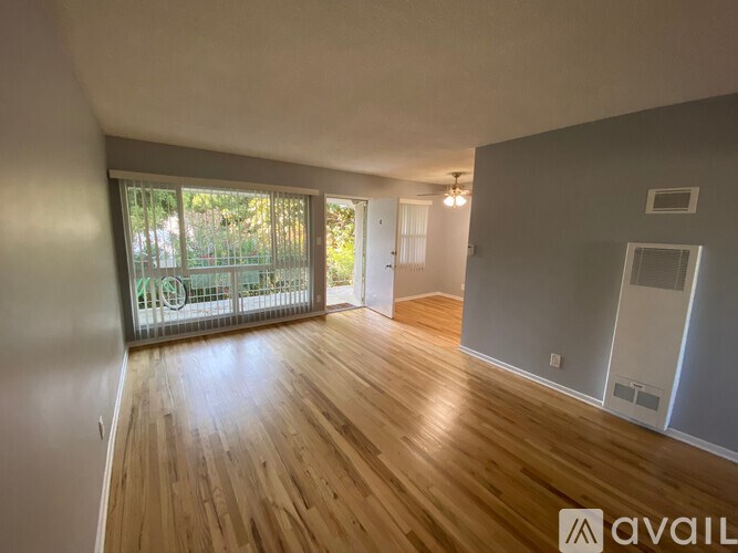 A room with wooden flooring and a sliding glass door leading to a balcony.