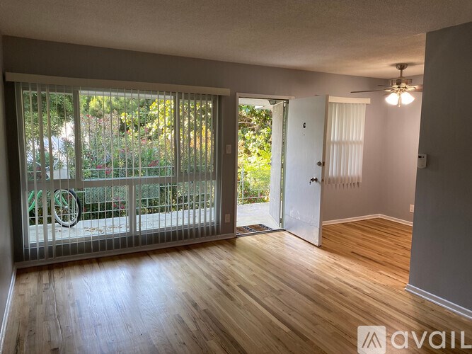 A room with wooden floors and a sliding glass door leading to a patio.