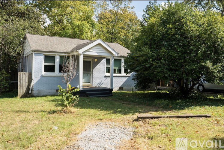 A small house with a gravel driveway in front.