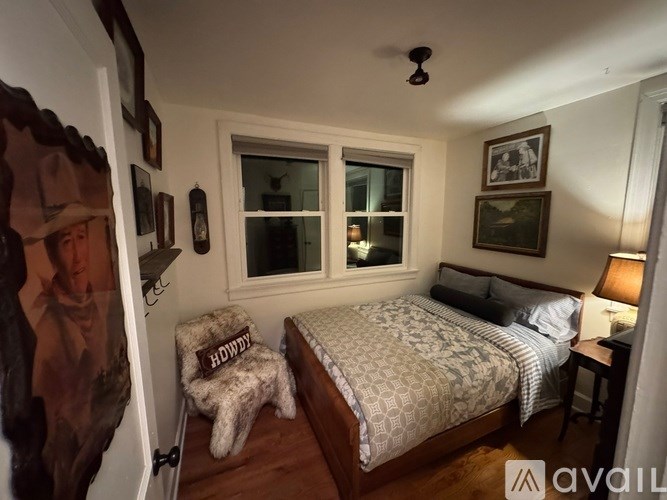 A bedroom with a bed, a chair, and a window.