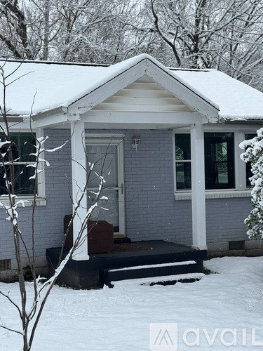 A house with a grey siding and a white roof is covered in snow.